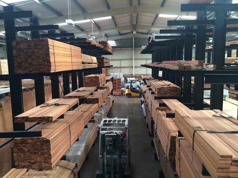 aisle at a warehouse with timber racking on both sides. Forklift truck going up the aisle